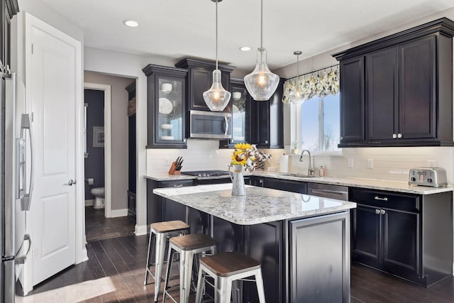 kitchen featuring a sink, stainless steel appliances, a breakfast bar, decorative backsplash, and a kitchen island