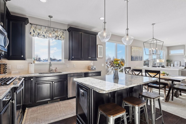 kitchen with a sink, appliances with stainless steel finishes, a chandelier, plenty of natural light, and recessed lighting