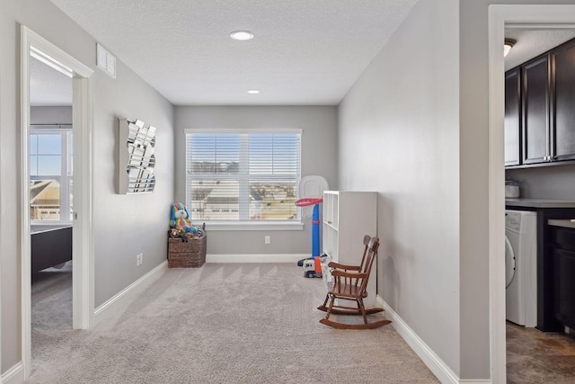 living area with washer / clothes dryer, carpet flooring, a textured ceiling, and baseboards