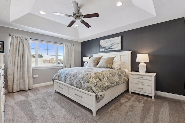 carpeted bedroom featuring a raised ceiling, baseboards, recessed lighting, and ceiling fan