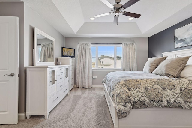 bedroom featuring light carpet, a tray ceiling, baseboards, ceiling fan, and recessed lighting