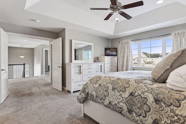 bedroom with carpet floors, a raised ceiling, baseboards, and ceiling fan