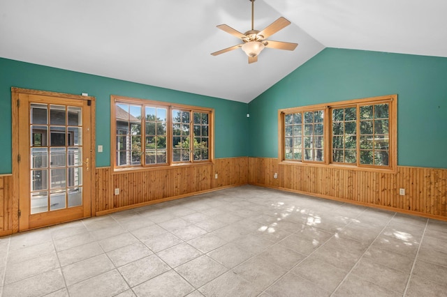 spare room featuring ceiling fan, wood walls, and vaulted ceiling