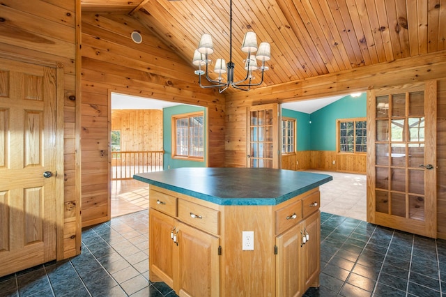 kitchen with pendant lighting, a notable chandelier, dark tile patterned flooring, a center island, and lofted ceiling