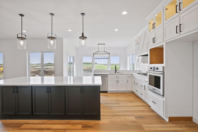 kitchen featuring pendant lighting, a center island, white cabinetry, and stainless steel appliances