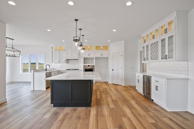 kitchen featuring appliances with stainless steel finishes, backsplash, wine cooler, white cabinets, and a kitchen island