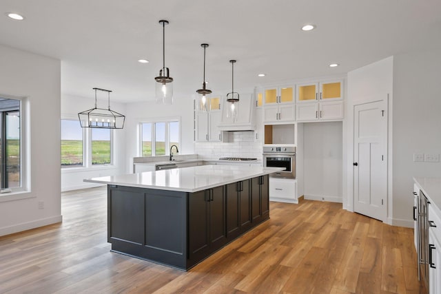 kitchen with white cabinets, a kitchen island, stainless steel appliances, and decorative light fixtures