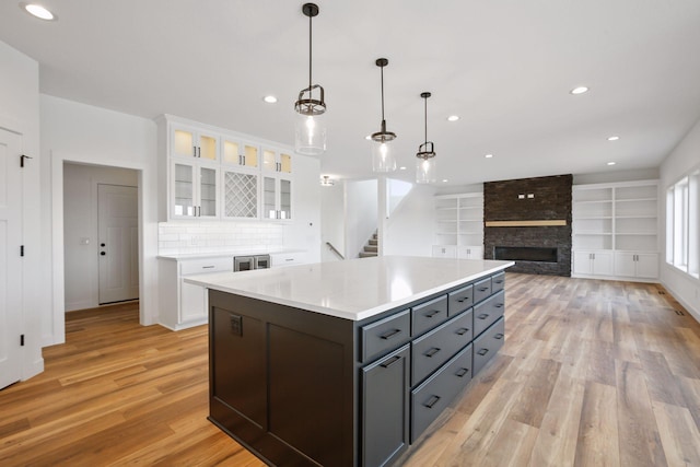 kitchen with a center island, pendant lighting, a fireplace, white cabinets, and light wood-type flooring