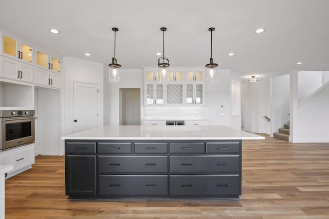 kitchen featuring a center island, stainless steel oven, white cabinets, and light hardwood / wood-style flooring