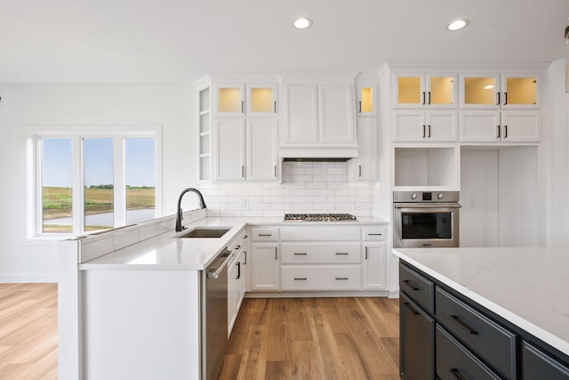 kitchen with white cabinetry, sink, light stone counters, and appliances with stainless steel finishes