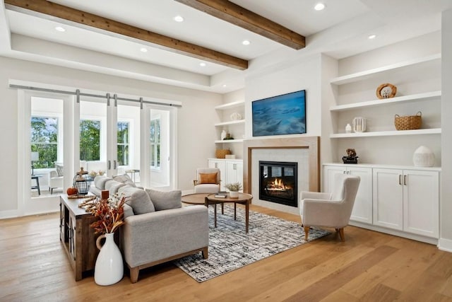 sitting room with beam ceiling, light wood-type flooring, built in features, and a wealth of natural light