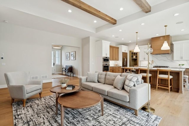 living room with beamed ceiling and light hardwood / wood-style flooring