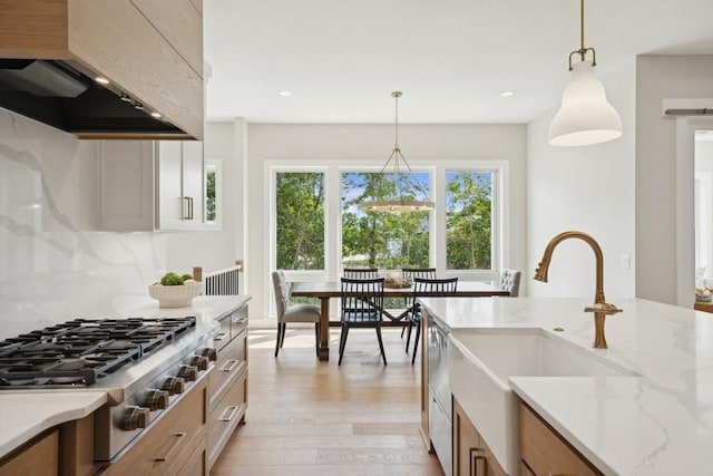 kitchen featuring pendant lighting, sink, light hardwood / wood-style flooring, light stone countertops, and custom range hood