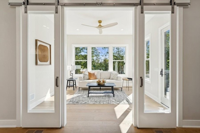 entryway with hardwood / wood-style floors, a barn door, and ceiling fan