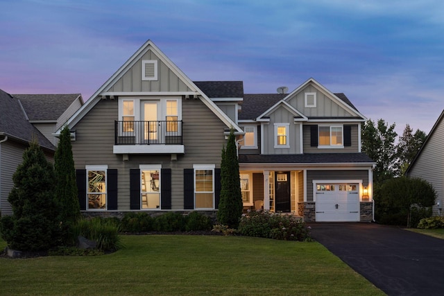 view of front of property featuring a garage, a lawn, and a balcony