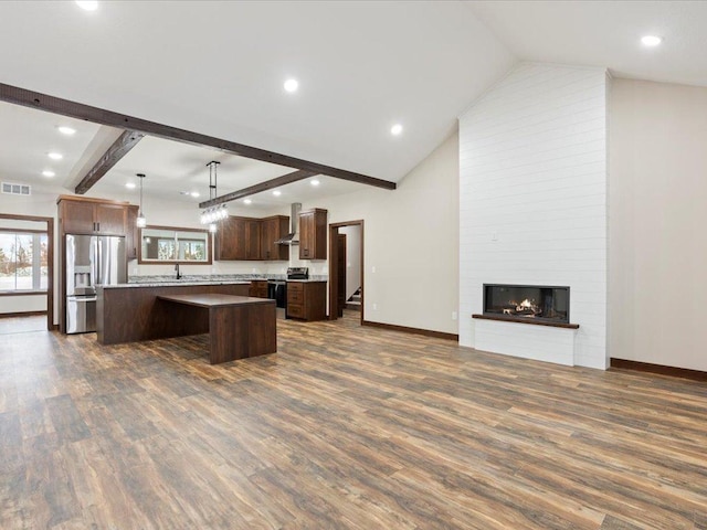 kitchen with pendant lighting, stainless steel appliances, a kitchen island, and dark hardwood / wood-style floors