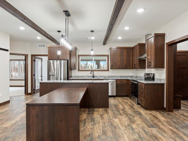 kitchen with stainless steel appliances, dark wood-type flooring, beamed ceiling, a center island, and hanging light fixtures