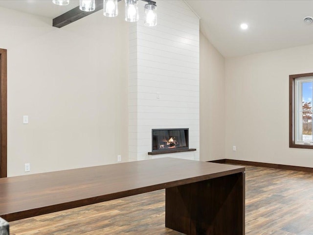 unfurnished living room featuring a large fireplace, vaulted ceiling, and dark wood-type flooring