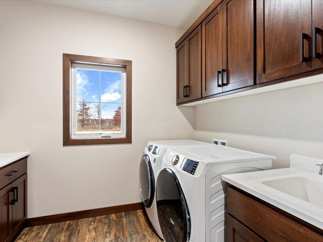 clothes washing area featuring dark hardwood / wood-style flooring, cabinets, sink, and washing machine and clothes dryer