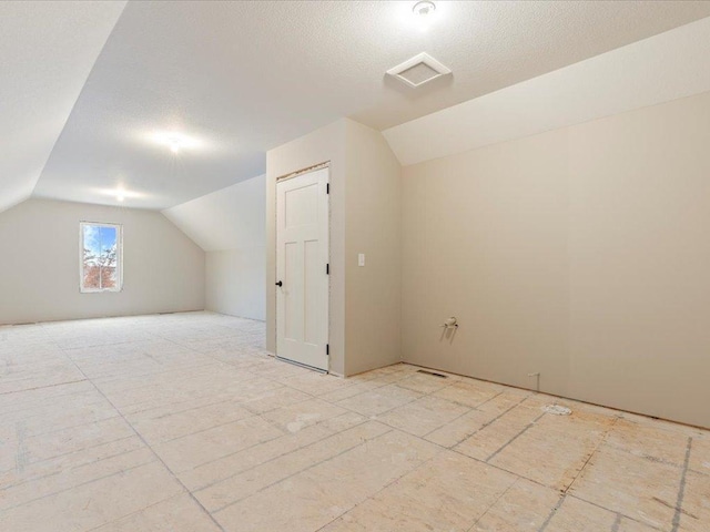 bonus room featuring a textured ceiling and vaulted ceiling