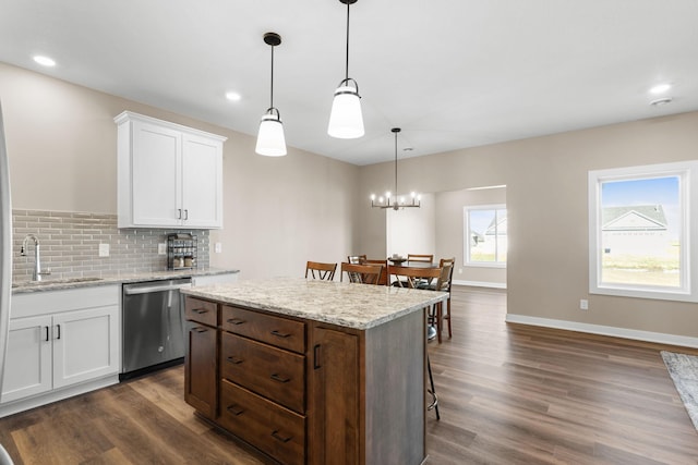 kitchen featuring dark wood-type flooring, white cabinets, sink, stainless steel dishwasher, and decorative light fixtures