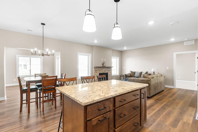 kitchen with plenty of natural light, decorative light fixtures, hardwood / wood-style flooring, and a center island