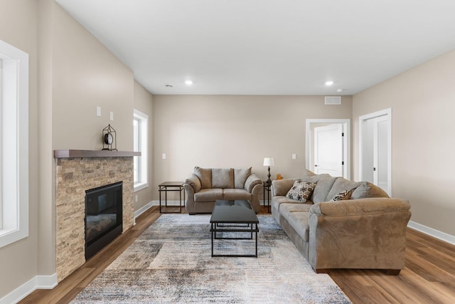 living room with a stone fireplace and hardwood / wood-style flooring