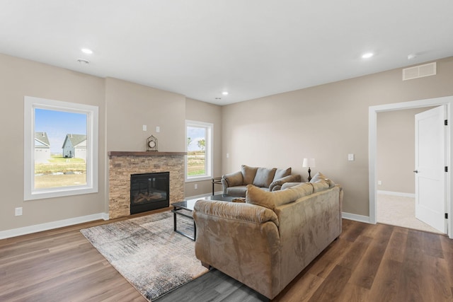 living room featuring a stone fireplace and dark hardwood / wood-style flooring