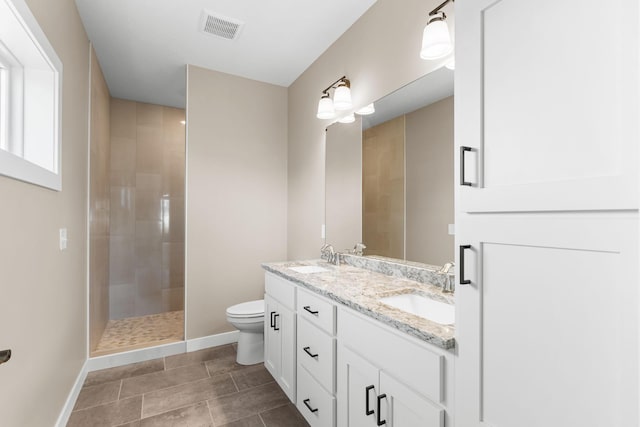 bathroom featuring tile patterned flooring, vanity, toilet, and tiled shower