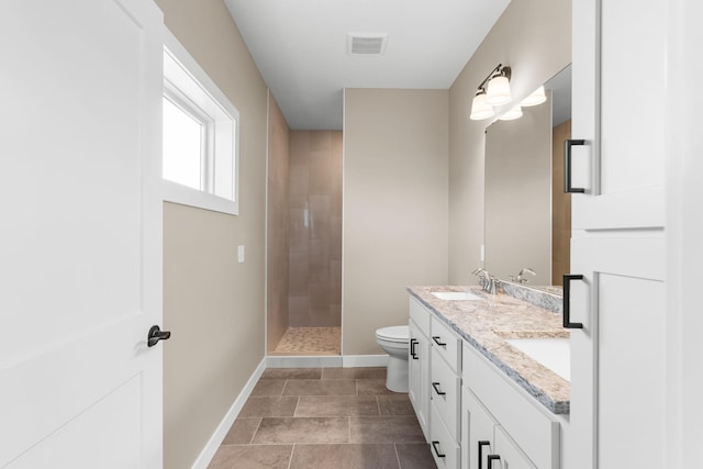 bathroom featuring vanity, toilet, and tiled shower