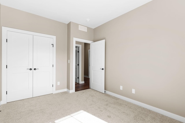 unfurnished bedroom featuring light colored carpet and a closet