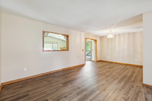 empty room featuring a notable chandelier, a textured ceiling, and hardwood / wood-style flooring