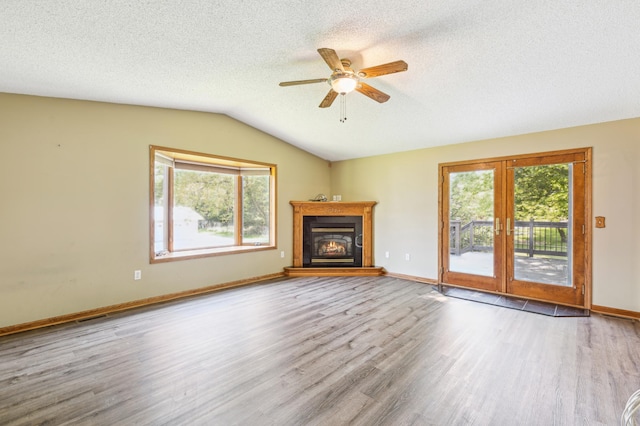 unfurnished living room with vaulted ceiling, ceiling fan, hardwood / wood-style flooring, and a textured ceiling