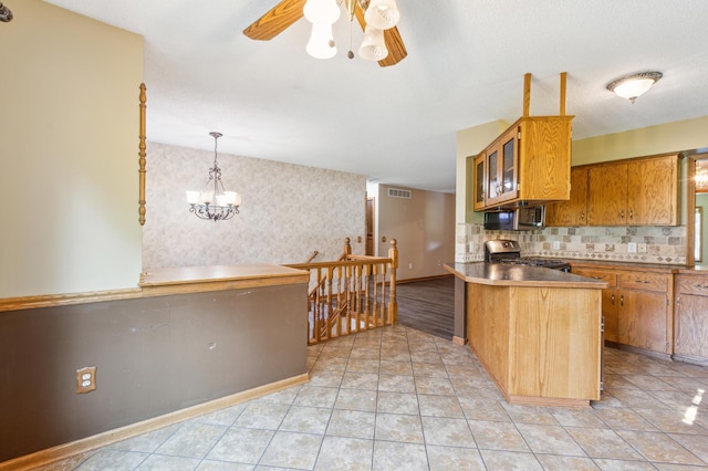 kitchen with hanging light fixtures, kitchen peninsula, backsplash, stainless steel appliances, and ceiling fan with notable chandelier