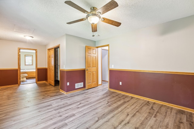 unfurnished room featuring light hardwood / wood-style floors, ceiling fan, and a textured ceiling