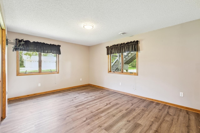 unfurnished room featuring a textured ceiling and light hardwood / wood-style floors