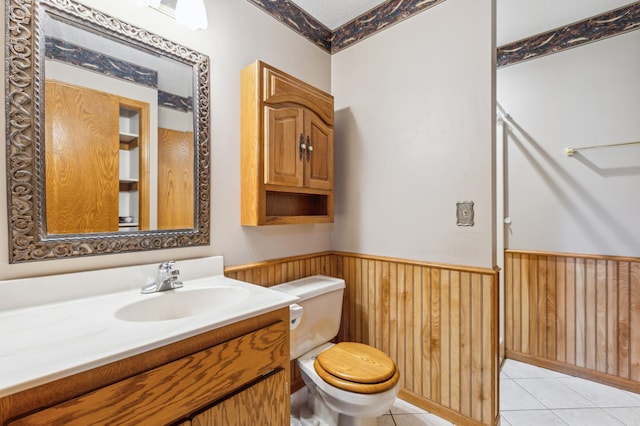 bathroom with vanity, wooden walls, tile patterned flooring, and toilet