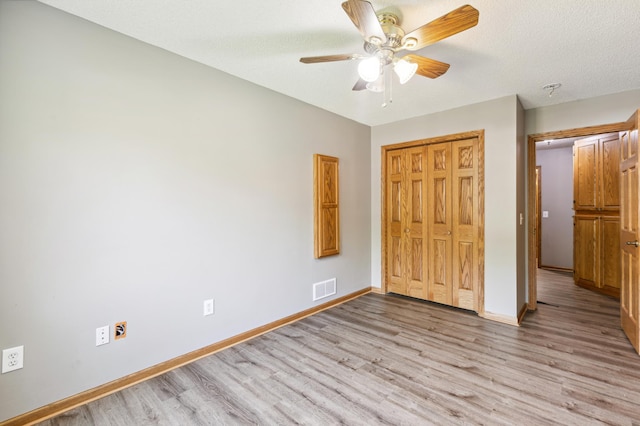 unfurnished bedroom with ceiling fan, a textured ceiling, a closet, and light hardwood / wood-style floors