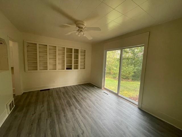 unfurnished room with dark wood-type flooring and ceiling fan