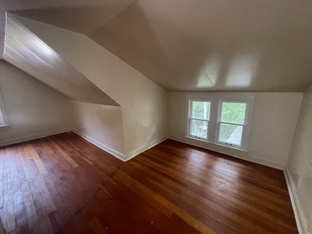 bonus room with lofted ceiling and dark hardwood / wood-style flooring