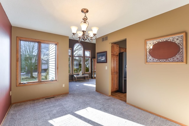 carpeted empty room with a notable chandelier