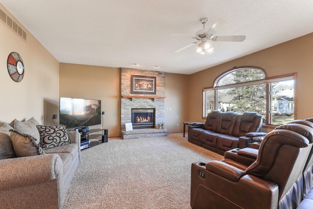 carpeted living room with ceiling fan, a fireplace, and a textured ceiling