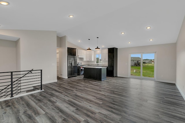 kitchen with lofted ceiling, dark hardwood / wood-style floors, stainless steel appliances, decorative light fixtures, and a center island