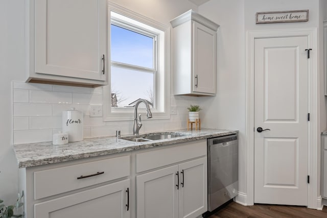 kitchen with white cabinetry, dark hardwood / wood-style flooring, sink, light stone countertops, and stainless steel dishwasher