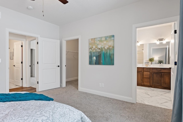 bedroom featuring ensuite bathroom, light carpet, a walk in closet, a closet, and ceiling fan