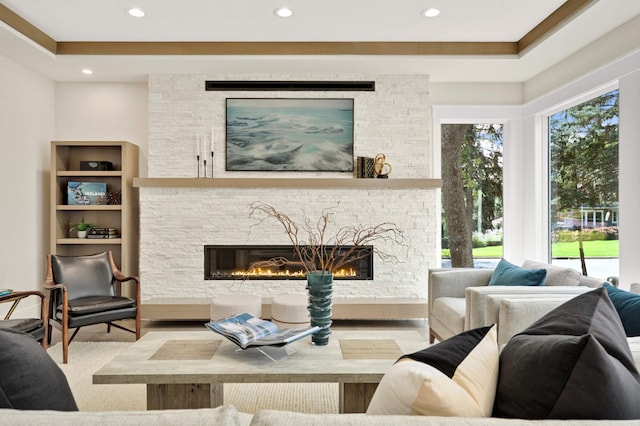 living room with a fireplace, a tray ceiling, and light hardwood / wood-style flooring