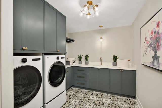 washroom with cabinets, an inviting chandelier, washer and clothes dryer, and sink