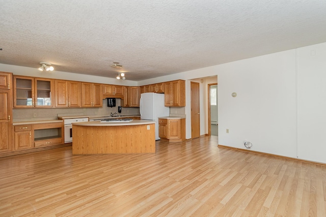 kitchen featuring light wood-type flooring, white appliances, a kitchen island, and a textured ceiling