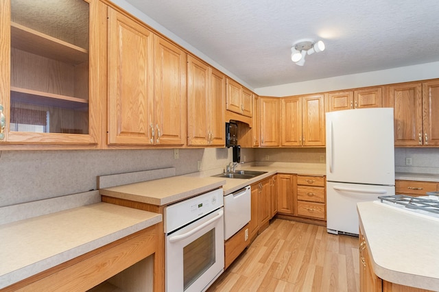 kitchen featuring a textured ceiling, sink, white appliances, and light hardwood / wood-style floors