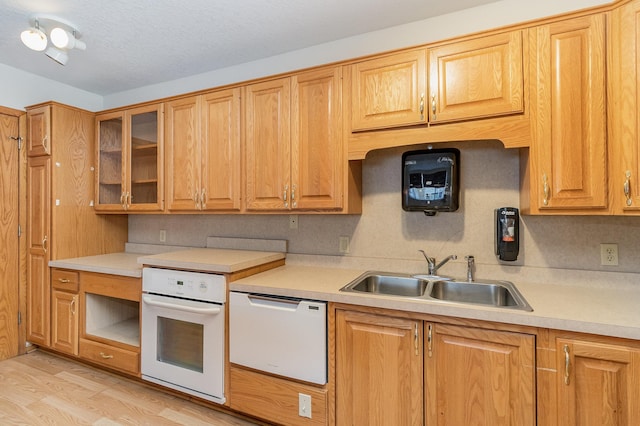 kitchen with backsplash, light wood-type flooring, white appliances, sink, and a textured ceiling